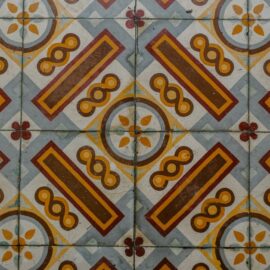Patterned encaustic-style floor tiles in ochre and blue